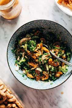 a bowl filled with salad sitting on top of a table next to other food items