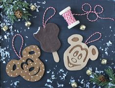 christmas ornaments made out of felt and wood on a black background with pine cones, twine spools and thread