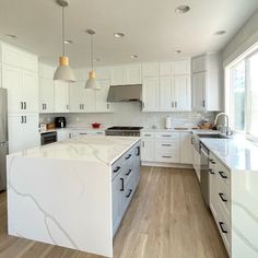 a large kitchen with white cabinets and marble counter tops, along with stainless steel appliances