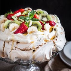 a dessert dish with fruit on top and whipped cream in the middle, sitting on a table