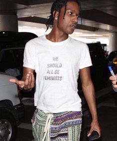 a man with dreadlocks wearing a t - shirt that says we should all be feminist