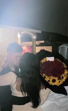 two people standing next to each other in front of a cake on a table with sunflowers