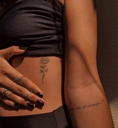 a woman's stomach with tattoos on it and a rose tattooed on the side