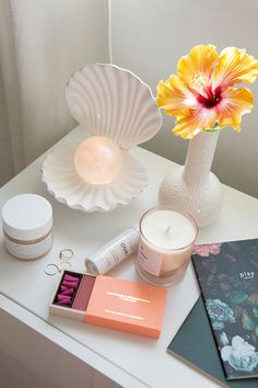 a white table topped with a vase filled with flowers next to candles and other items