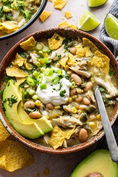 a bowl of chicken tortilla soup with avocado and sour cream on the side