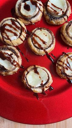 there are many desserts on the red plate with chocolate drizzled over them