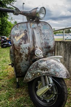 an old scooter is parked in the grass