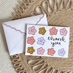 a thank you card with flowers on it sitting next to an envelope that says, thank you