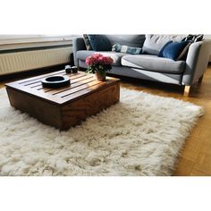 a living room with a couch, coffee table and rug on the floor in front of it