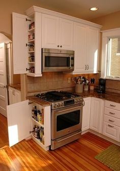 a kitchen with white cabinets and stainless steel stove top oven in the middle of it