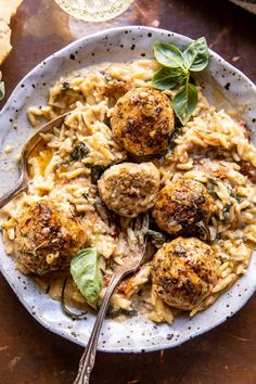 pasta with meatballs and spinach in a white bowl on a wooden table top