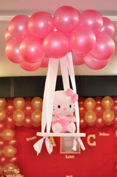 a hello kitty balloon is suspended from the ceiling with pink and white balloons above it