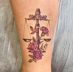 a woman's leg with a tattoo on it that has a scale and flowers on it