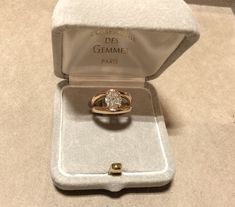 an open ring box with a diamond in it