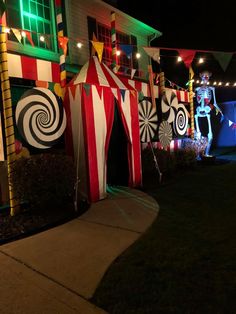 a circus tent is lit up in front of a house with lights and decorations on it