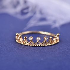 a gold ring with three small diamonds on the top and bottom, sitting on a blue surface