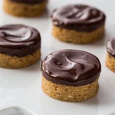 several cookies with chocolate frosting sitting on a white plate, ready to be eaten