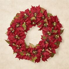 a christmas wreath with red poinsettis and gold bells hanging on a wall