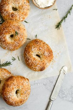 four bagels with rosemary sprinkled on top and two cups of cream cheese