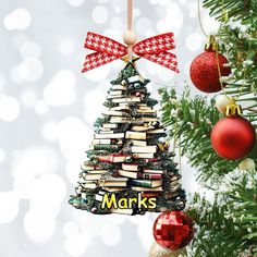 a christmas tree ornament with books on it and the words marks hanging from it