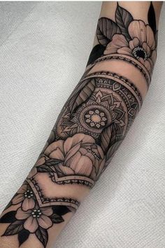 a woman's arm with tattoos on it and flowers in the middle of her arm