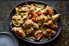 a plate full of chicken, artichokes and tomatoes next to a container