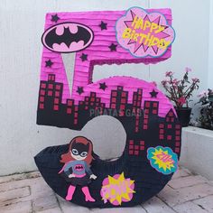 a pink and black birthday cake with the number 50 on it's side, decorated like a batgirl