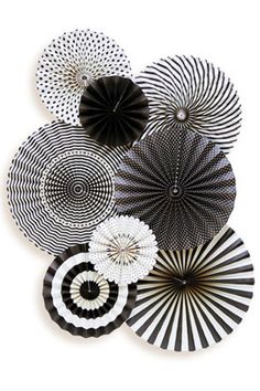 several black and white paper fans hanging on the wall in front of a white background