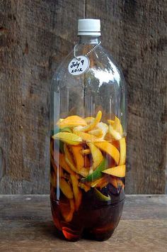 a glass bottle filled with liquid and cut up fruit in it's bottom half