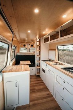 the interior of an rv with wood flooring and white cabinets