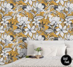 a white bed sitting next to a yellow wallpaper covered in flowers and berries on top of it