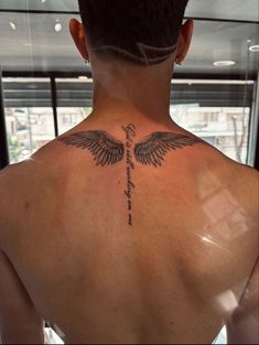 the back of a man's neck with a cross and wings tattoo on it