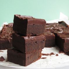 several pieces of chocolate fudge cake sitting on top of a white plate with frosting