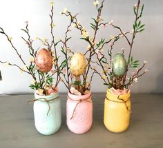 three painted mason jars filled with flowers and eggs