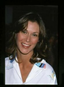 a woman in uniform smiling at the camera with an american flag on her collared shirt