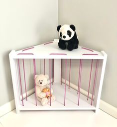 a stuffed panda bear sitting on top of a white shelf next to a teddy bear in a cage