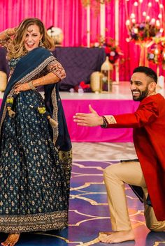 a man kneeling down next to a woman in a blue and gold dress on a stage