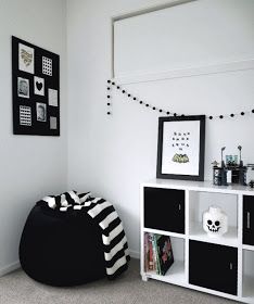 a black and white room with pictures on the wall, bookshelf and dog bed