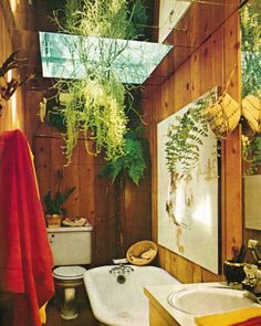 a bathroom with wood paneling and plants hanging over the bathtub, toilet and sink