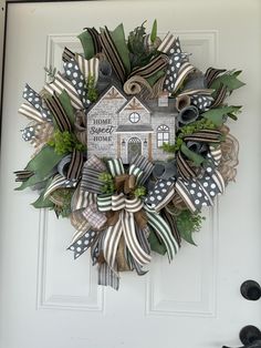 a wreath is hanging on the front door with ribbons and bows around it that says, home is where the heart is