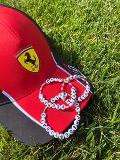 a red cap with beads and a ferrari logo on it laying in the green grass