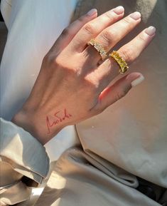 a woman's hand with a yellow diamond ring on her left wrist and the word love written in red ink