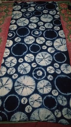 a blue and white tie - dyed table runner with circles on it, sitting on a red blanket