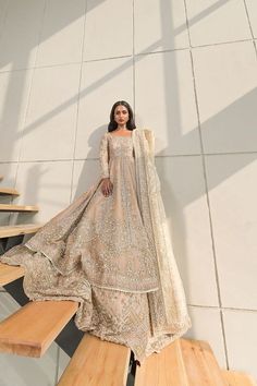 a woman in a long dress standing on some stairs