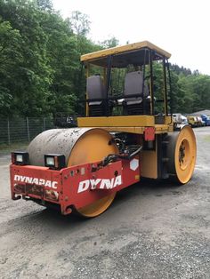 a large yellow and red machine sitting on top of a gravel road