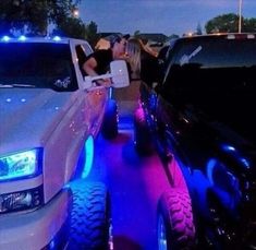 two women are kissing in the back of their pickup truck with blue lights on it