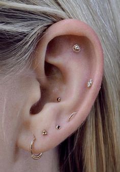 a close up of a person's ear with three different piercings on it