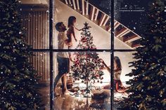 two people decorating a christmas tree through a window