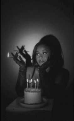 a woman holding a knife in front of a cake with lit candles on top of it