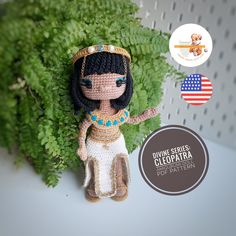 a crocheted doll sitting on top of a green plant next to a sticker that says divine service, clopria